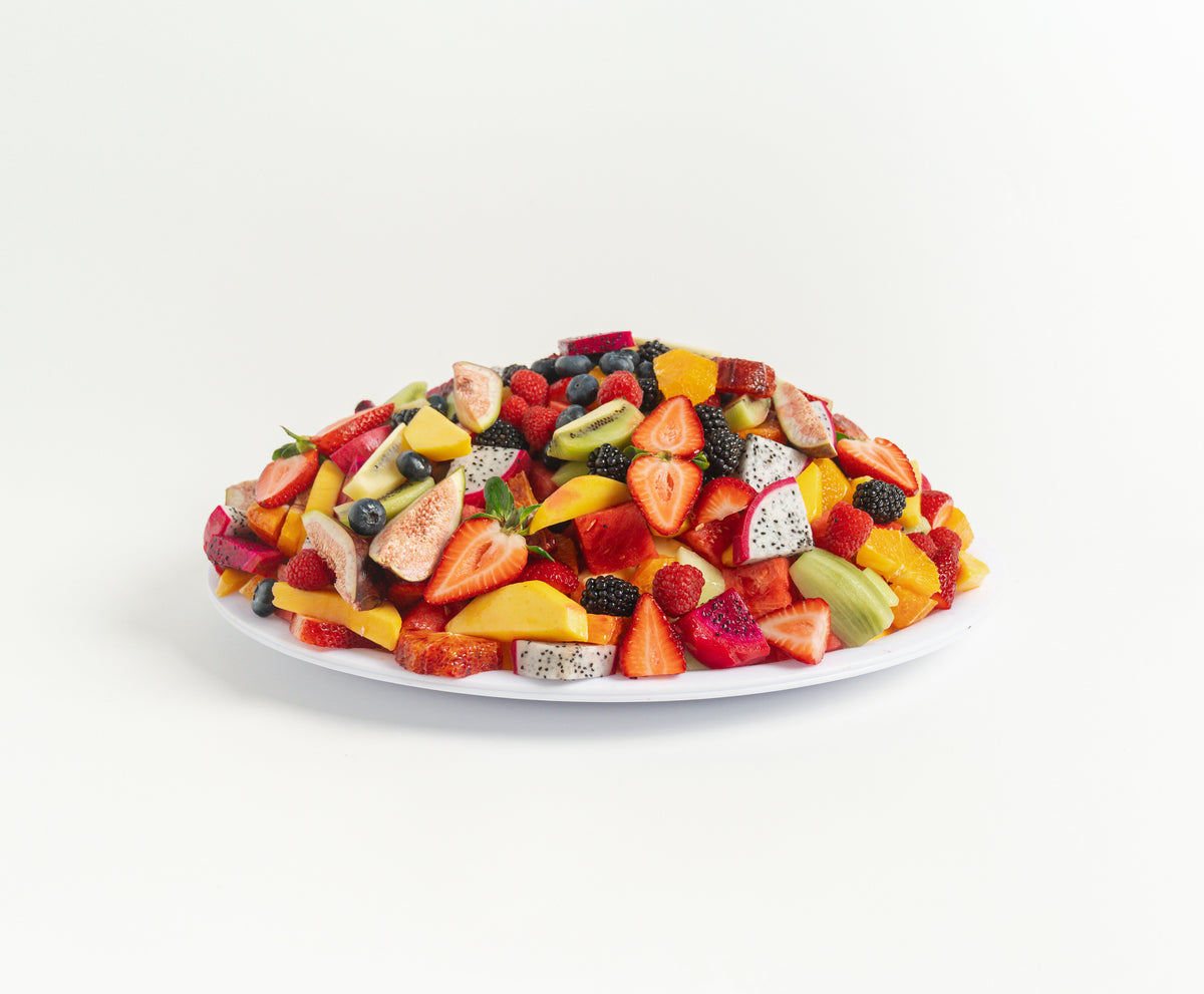 Colorful premium fruit salad on round platter, featuring fresh sliced fruits arranged beautifully, by Top Fruit Market.